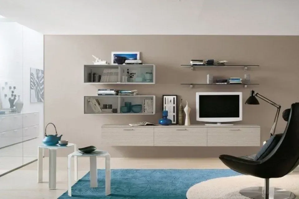 Soggiorno moderno con pareti neutre, mensole sospese in legno chiaro e tappeto blu.