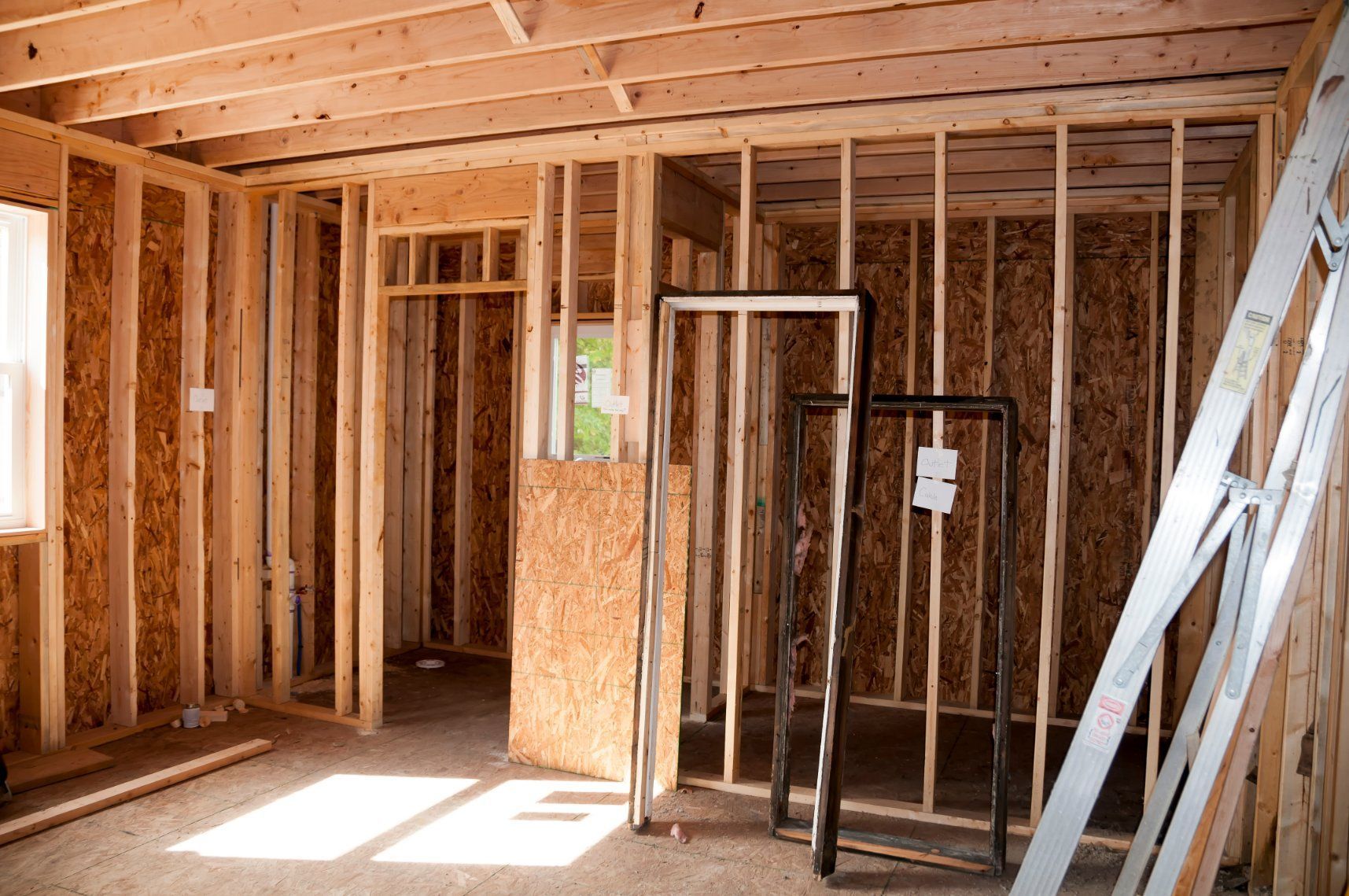 Interior of a room under construction, with wooden studs, unfinished walls, and door frames.