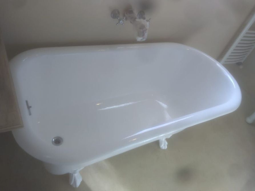 Bañera blanca con patas de garra en un baño, vista desde arriba.