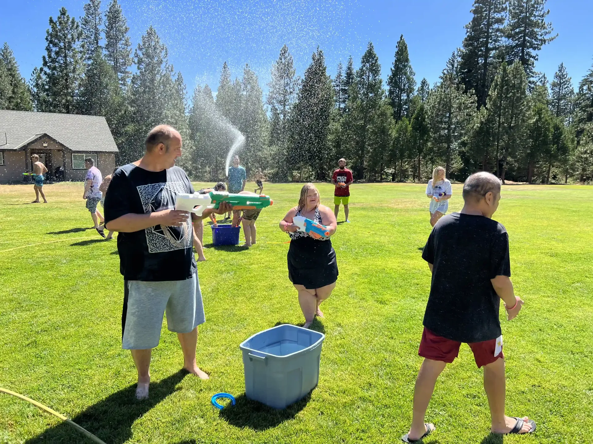 A group of people are playing with water in a field.