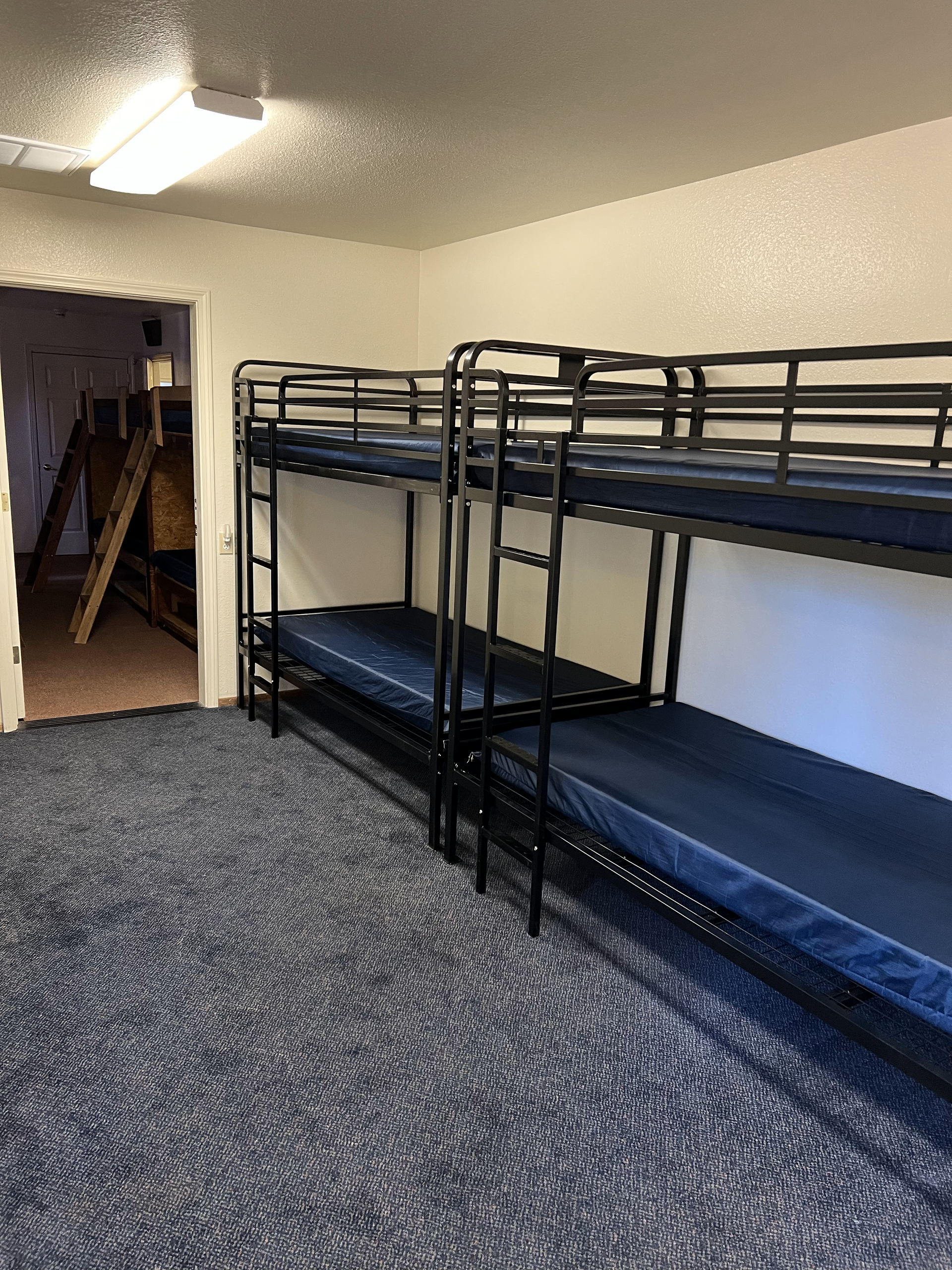 A room with bunk beds and blue mattresses in it.