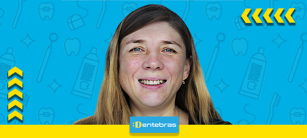 Mulher sorridente em fundo azul com setas amarelas e uma etiqueta DEN TEBRAS abaixo.