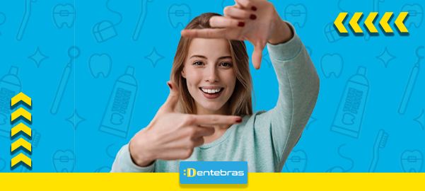 Pessoa sorridente emoldurando a palavra DENTBRAS em um fundo azul brilhante com detalhes em amarelo.