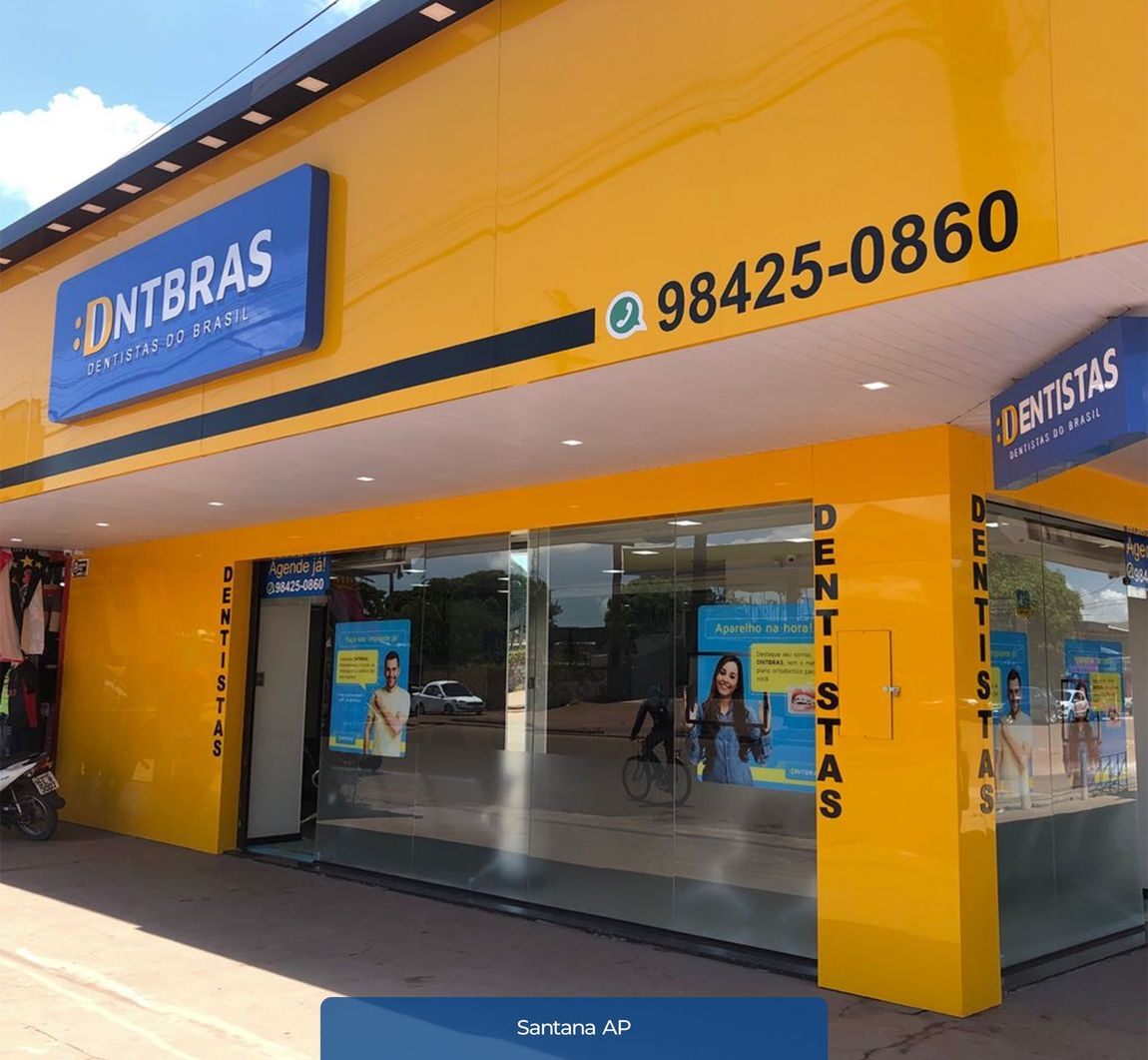Fachada amarela com entrada de vidro e placas azuis com a inscrição “DONTBRAS”, com a placa “Dentistas” e um número de telefone acima.