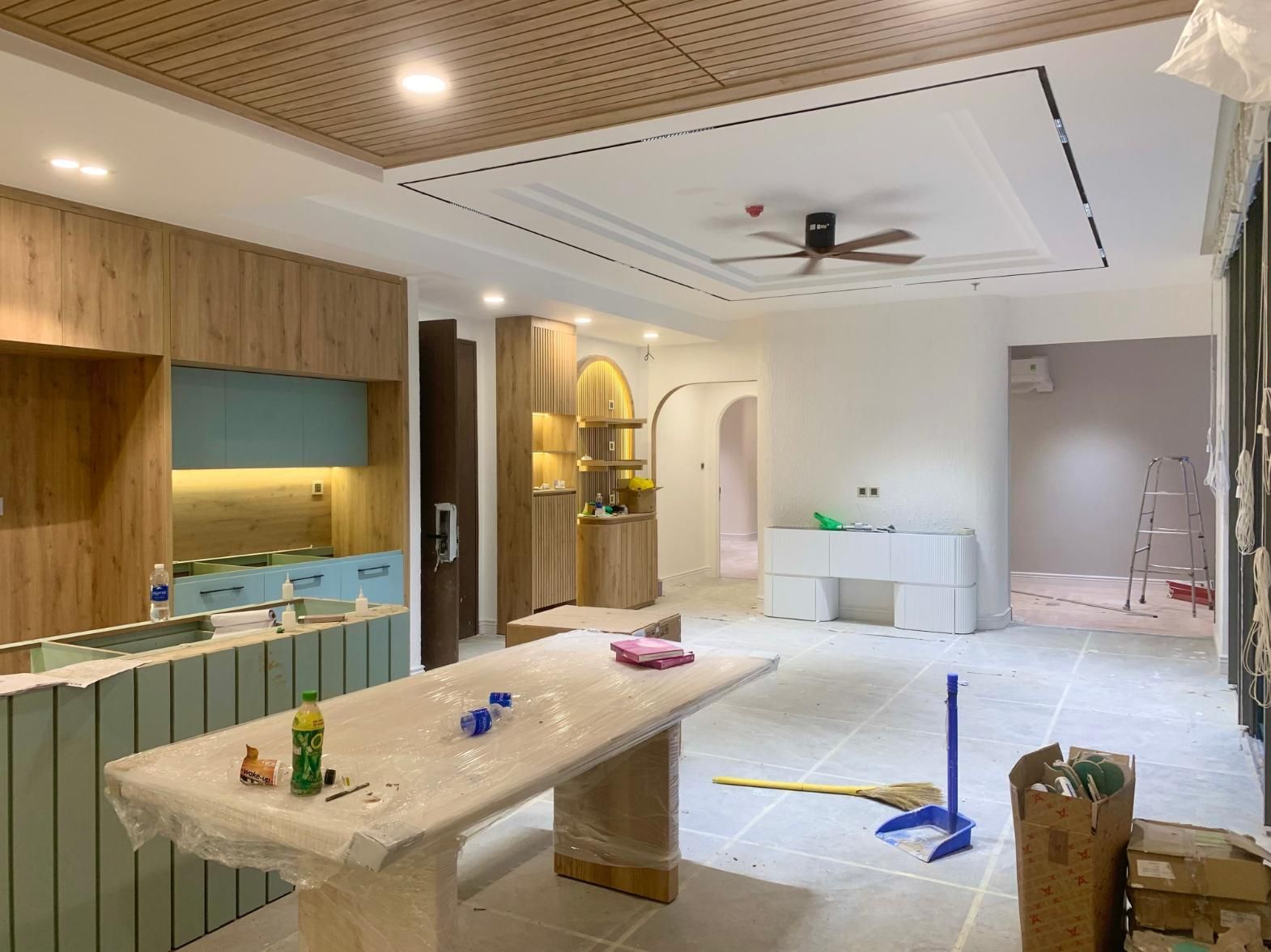 Modern kitchen under renovation with marble island, exposed flooring, and a ladder at the back