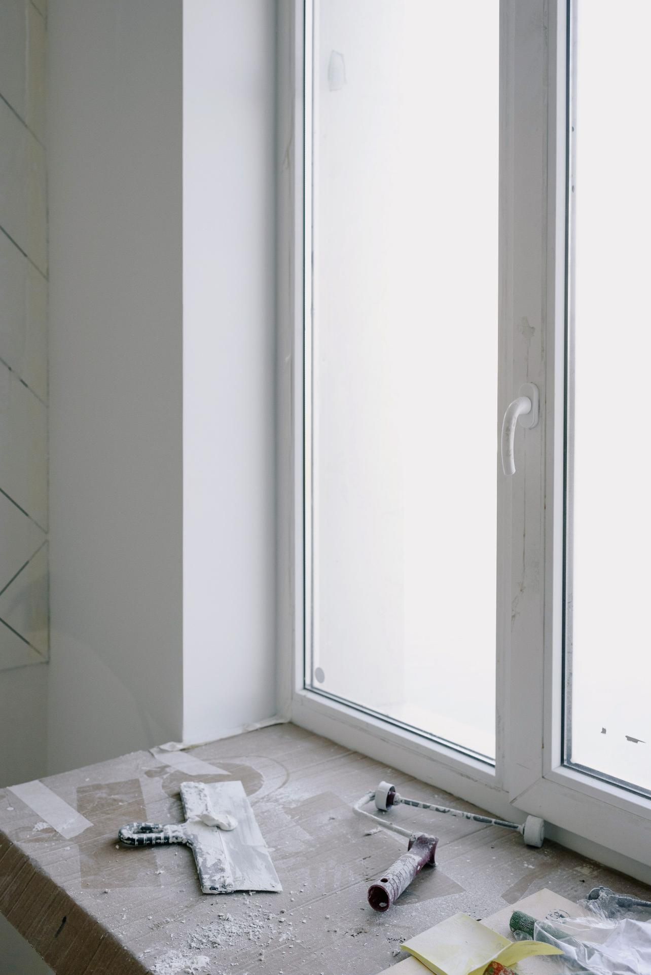 Bathroom under renovation with window, tile floor, and construction debris scattered on the ground
