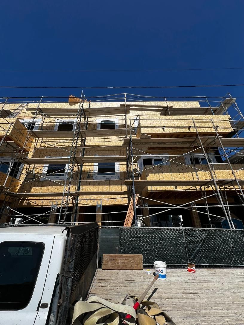 Partially constructed apartment building with scaffolding under a clear blue sky