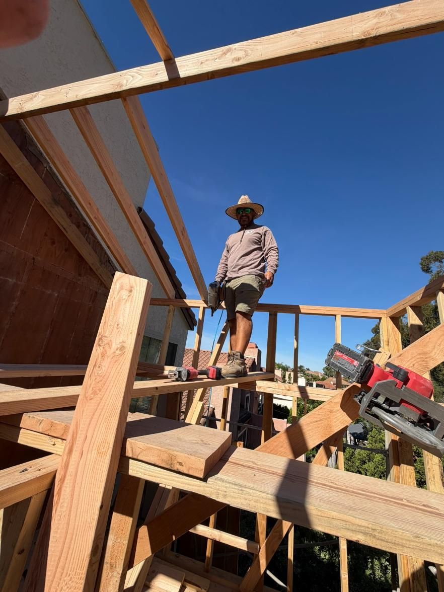 Worker standing on wooden framing at a construction site under a clear blue sky