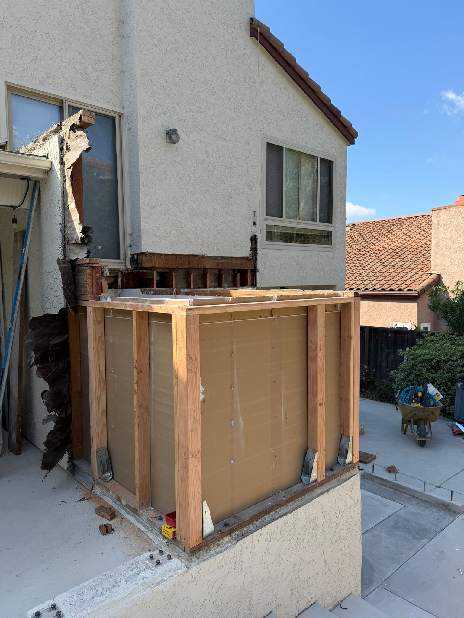 Wrapped appliance on a porch beside a house under construction