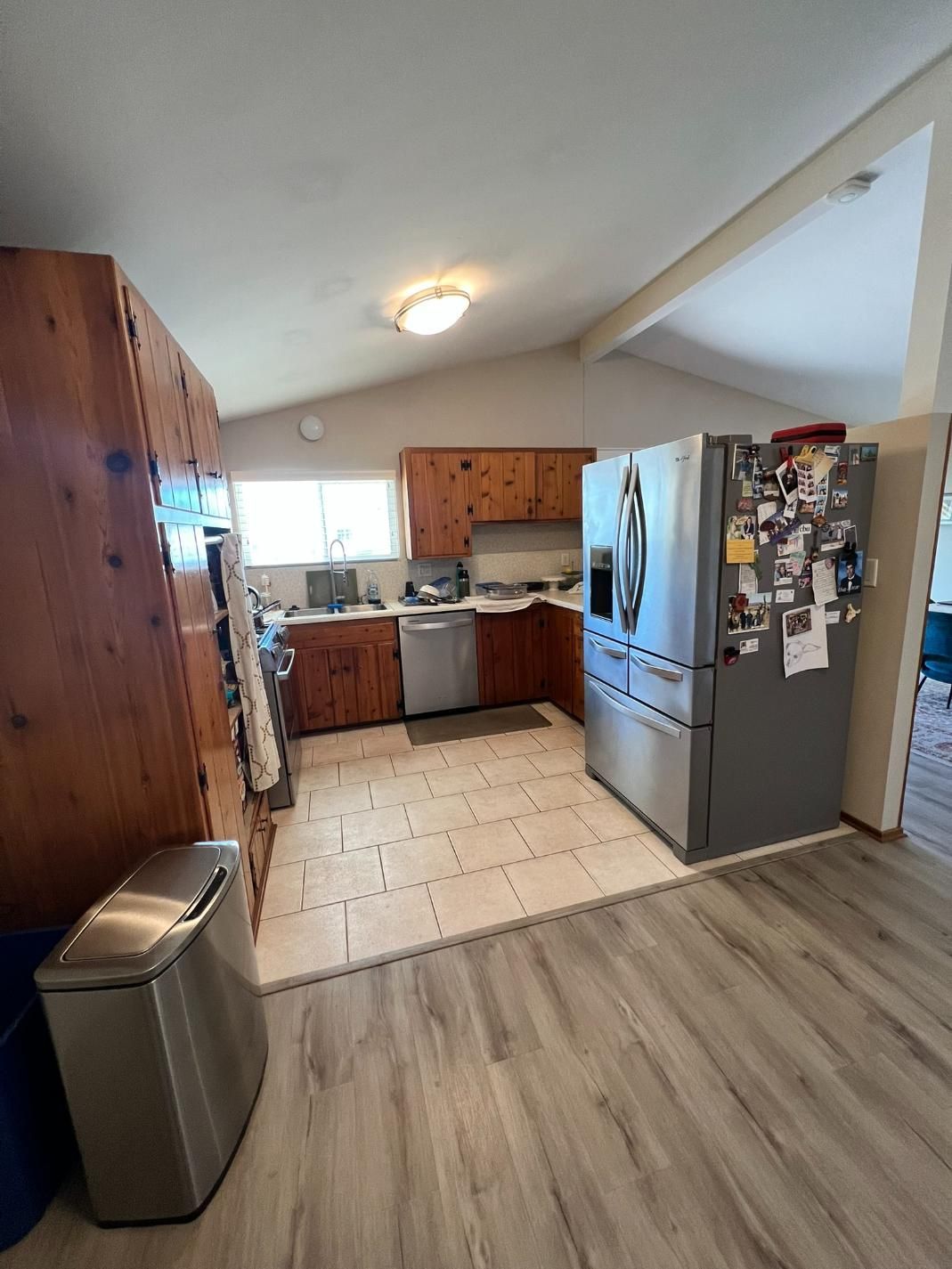 Kitchen with wood cabinets, tiled floor, and a stainless steel refrigerator next to a dining area.