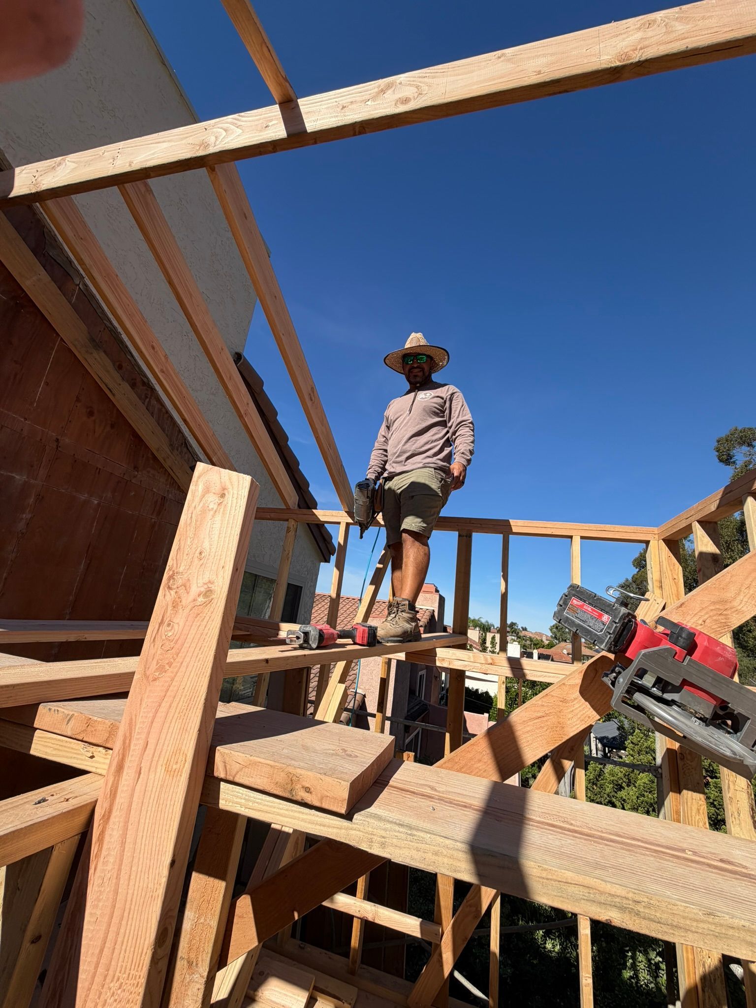 Worker standing on wooden framing at a construction site under a clear blue sky