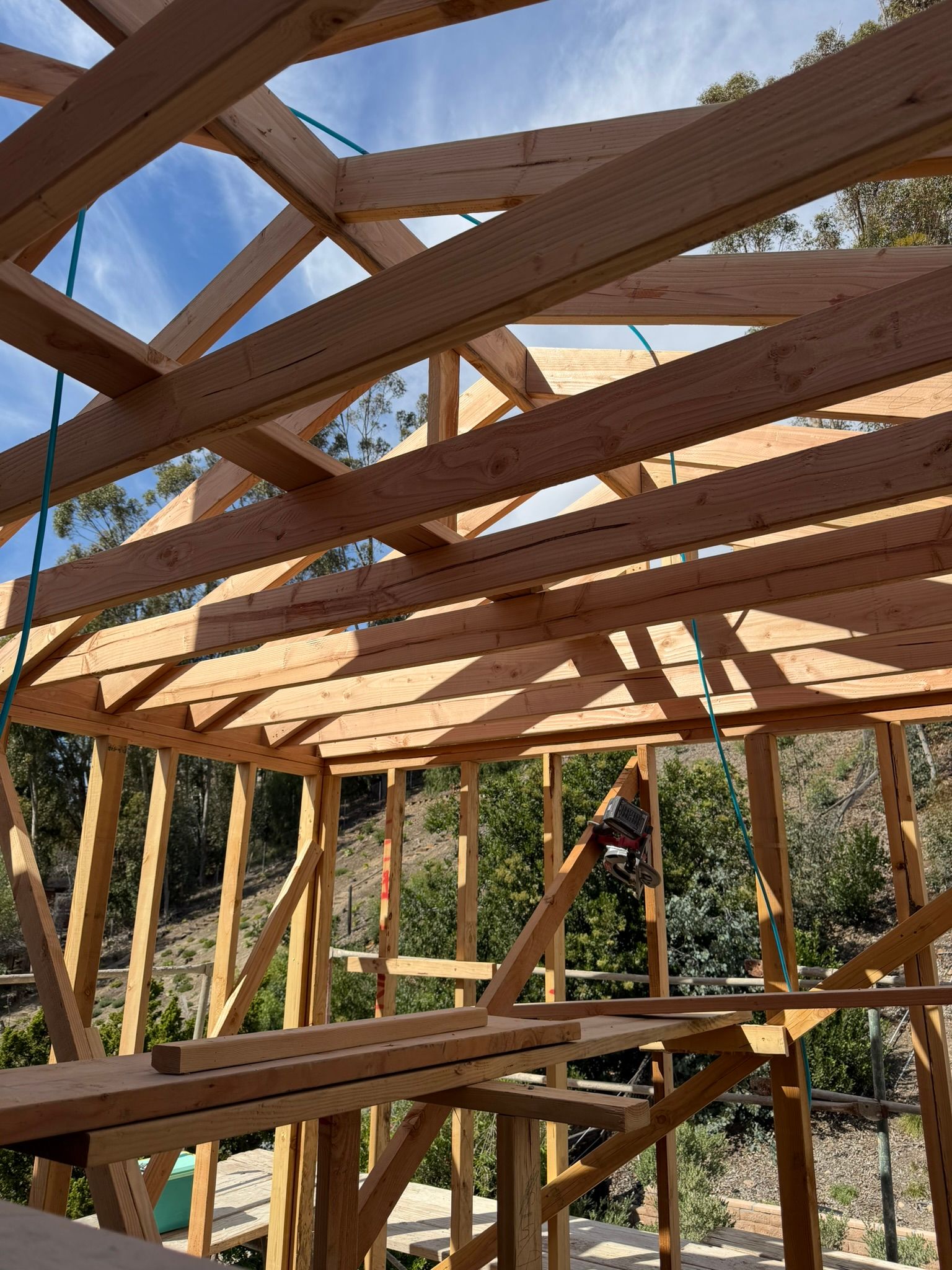 Partially framed wooden roof structure under construction against a blue sky