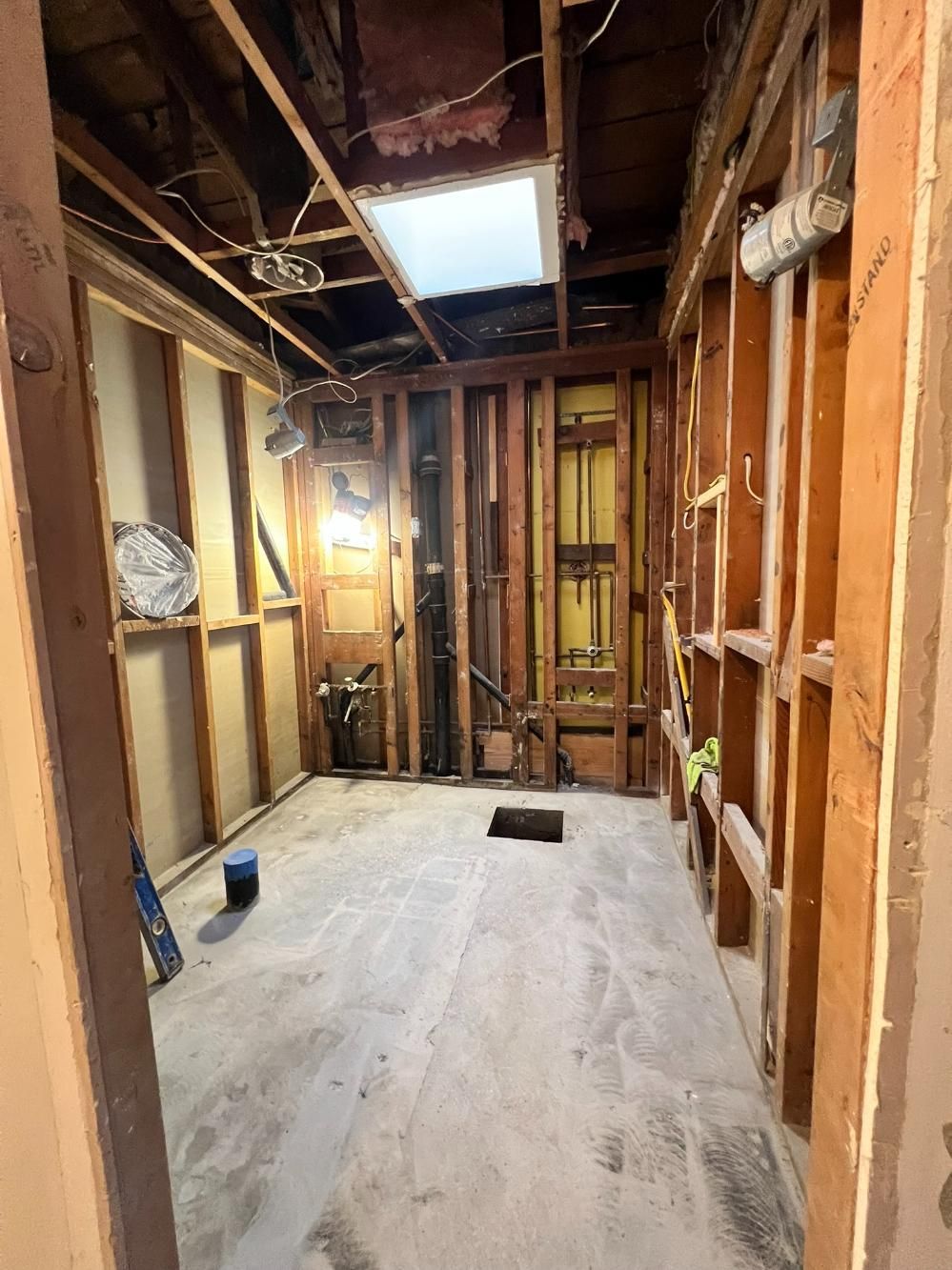 Unfinished interior room with exposed wooden framing, insulation, and a skylight opening in the ceiling.
