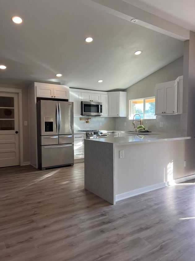 Bright modern kitchen with white cabinets, stainless steel appliances, and a central island.