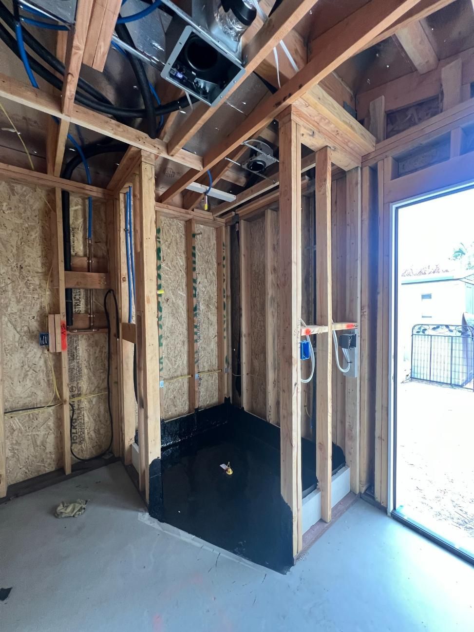 Unfinished room with exposed studs, insulation, and open doorway letting in bright light