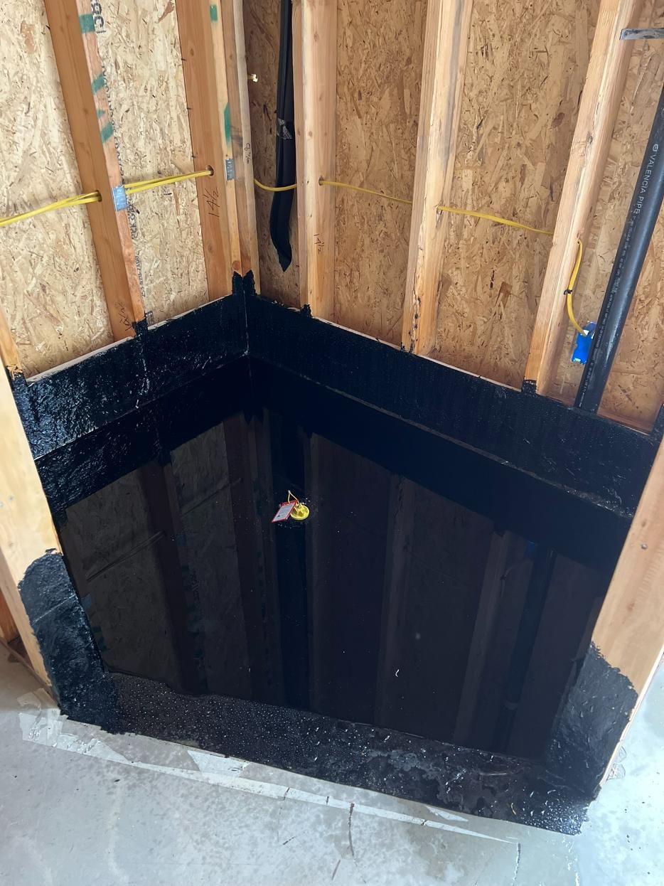 Open floor framing around a dark square stairwell opening in an unfinished room