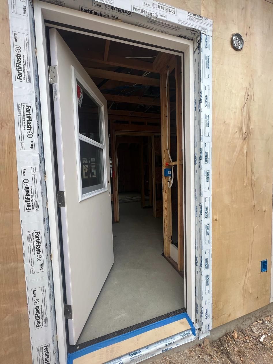 Open white door at a construction site, with exposed framing visible inside.