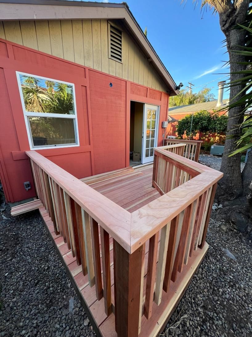 Wooden ramp with railings leading to a red house entrance and window