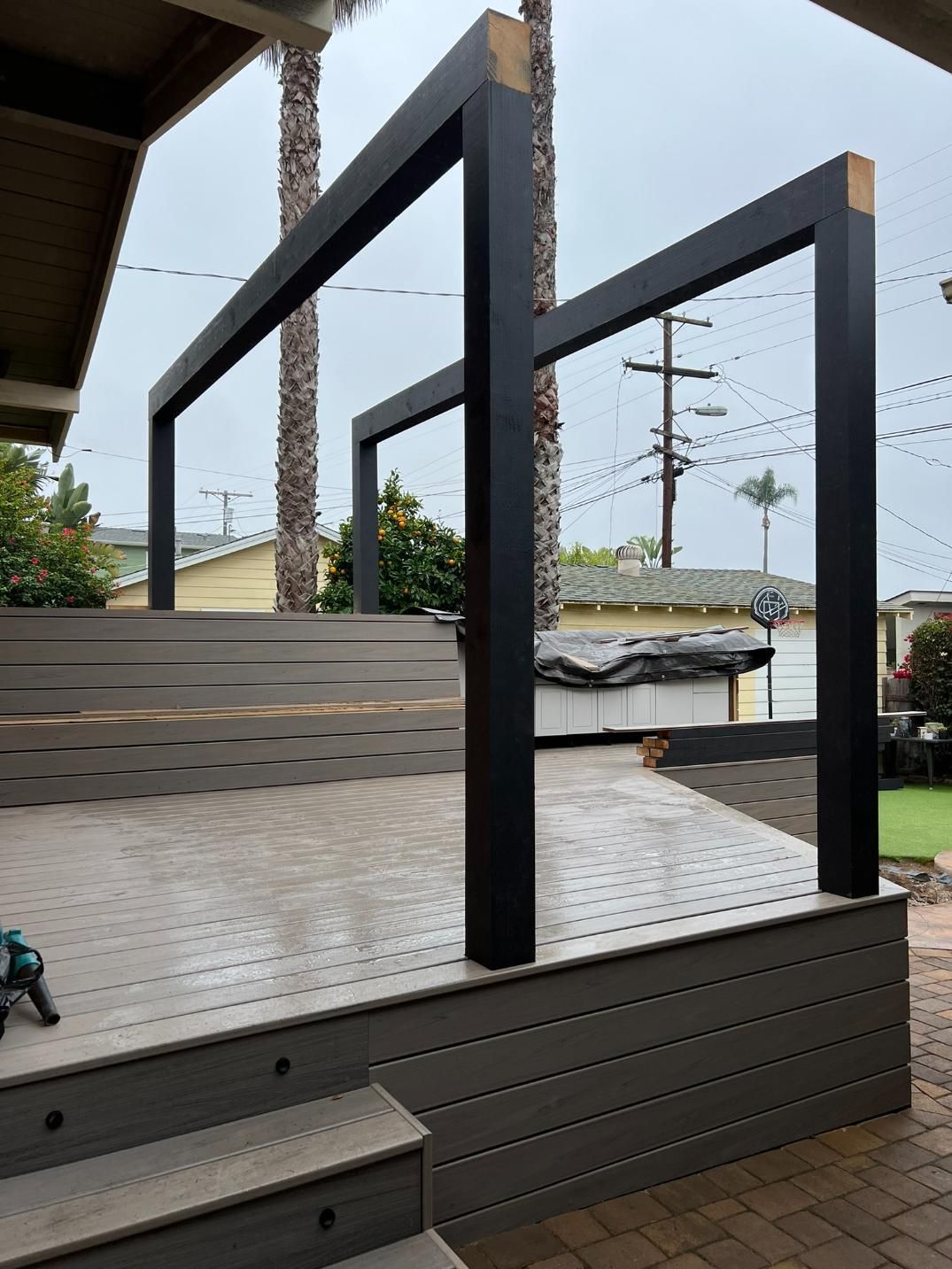 Empty outdoor deck with black railings and metal floor, overlooking a street and power lines.