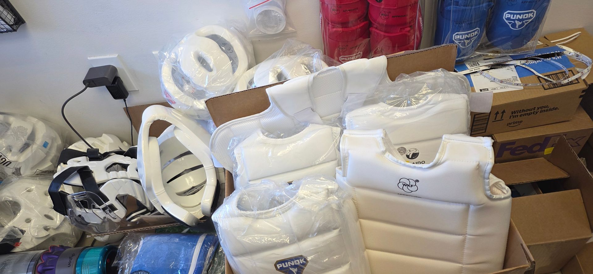 Piles of white foam packaging materials stacked in a cluttered storage area with boxes and rolls nearby