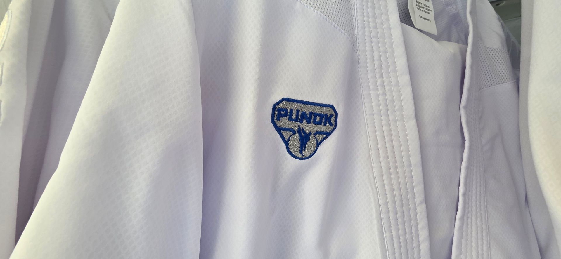 Close-up of a white jacket with a blue-and-yellow shield patch on the chest