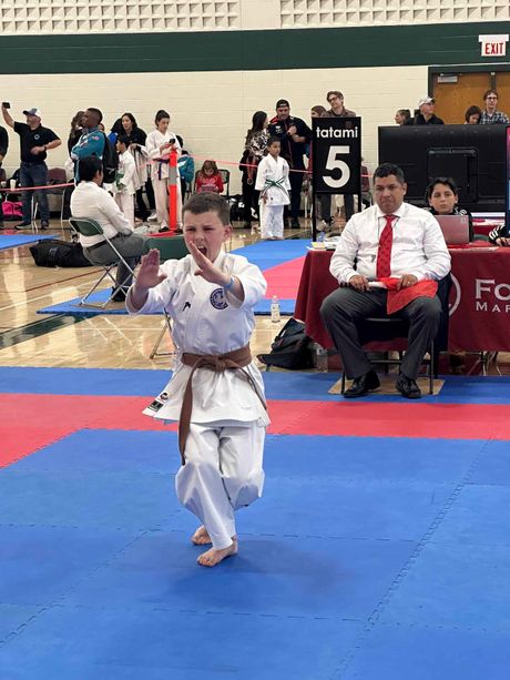 A man in a white karate uniform with a black belt is practicing karate.