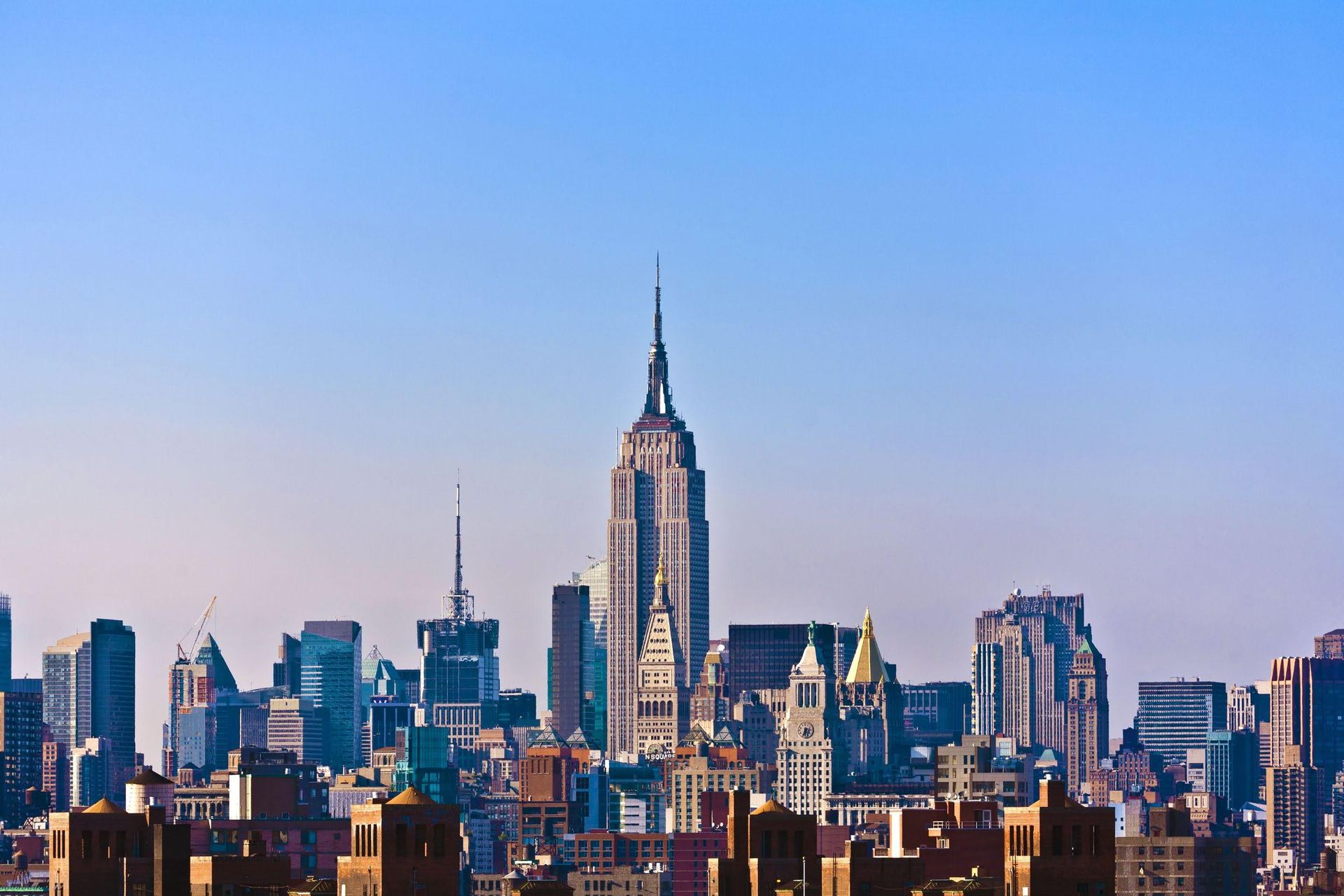 A shot of New York City from the outskirts, featuring a clear blue sky in the afternoon.