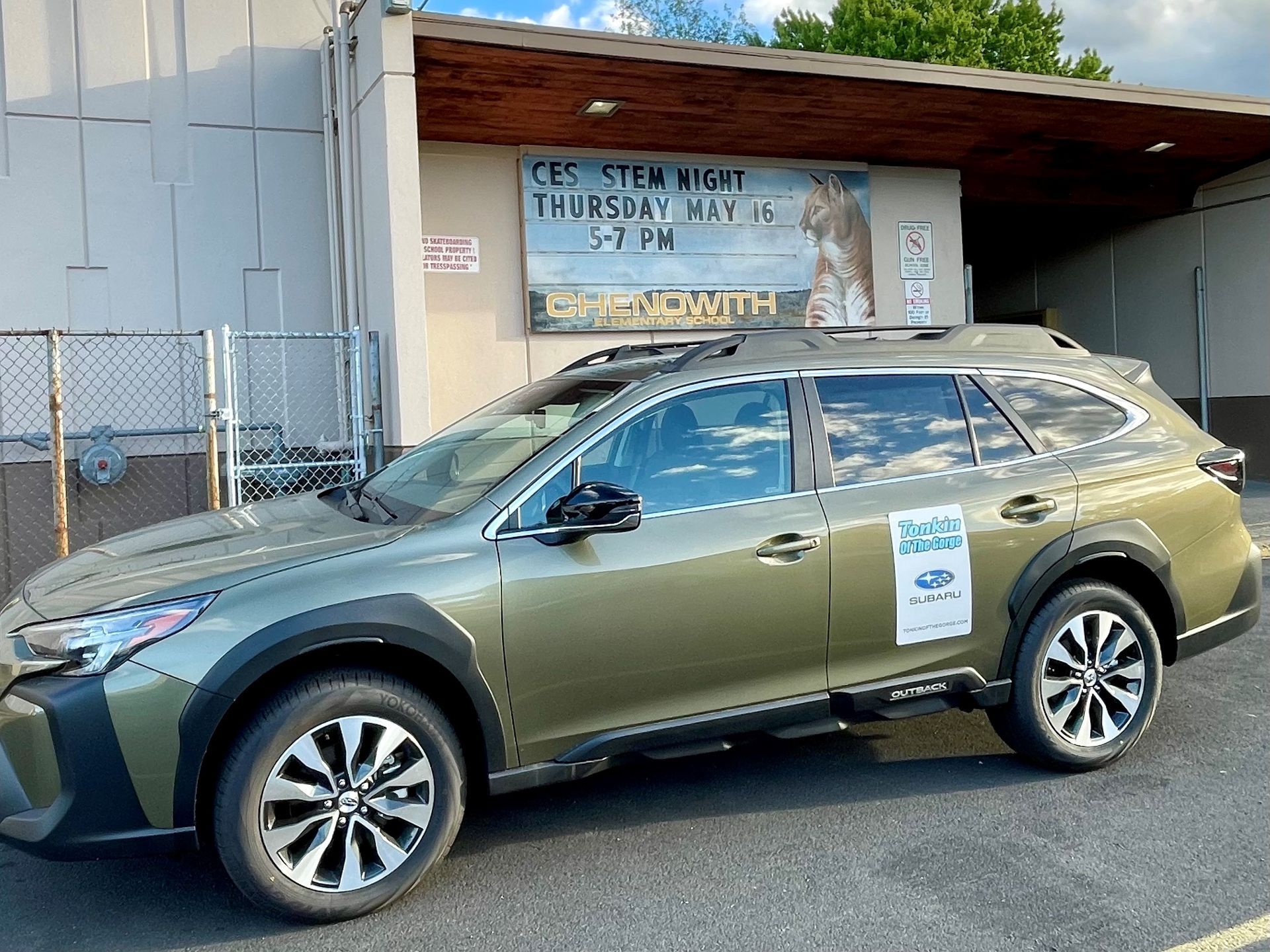 A green suv is parked in front of a building.