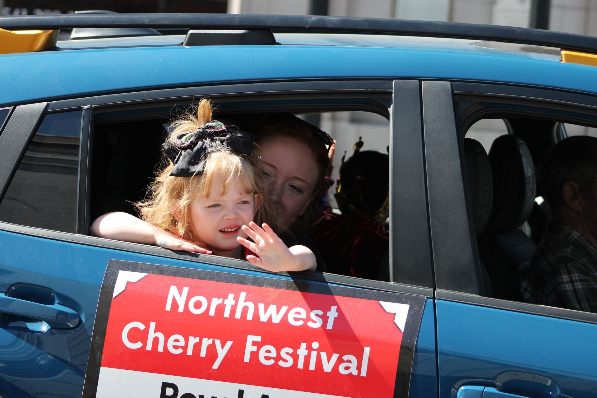 A woman and child in a car with a sign that says northwest cherry festival