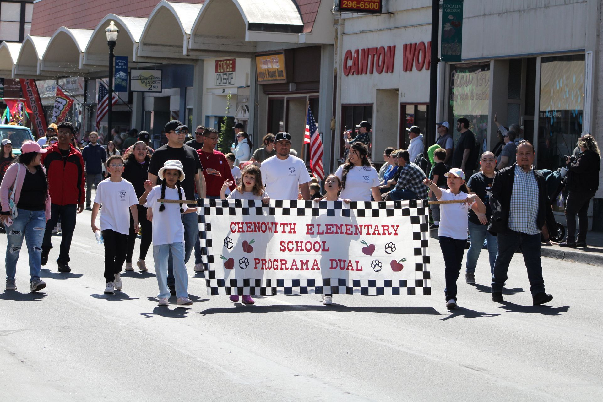 A group of people are marching down a street holding a banner that says trudette elementary school