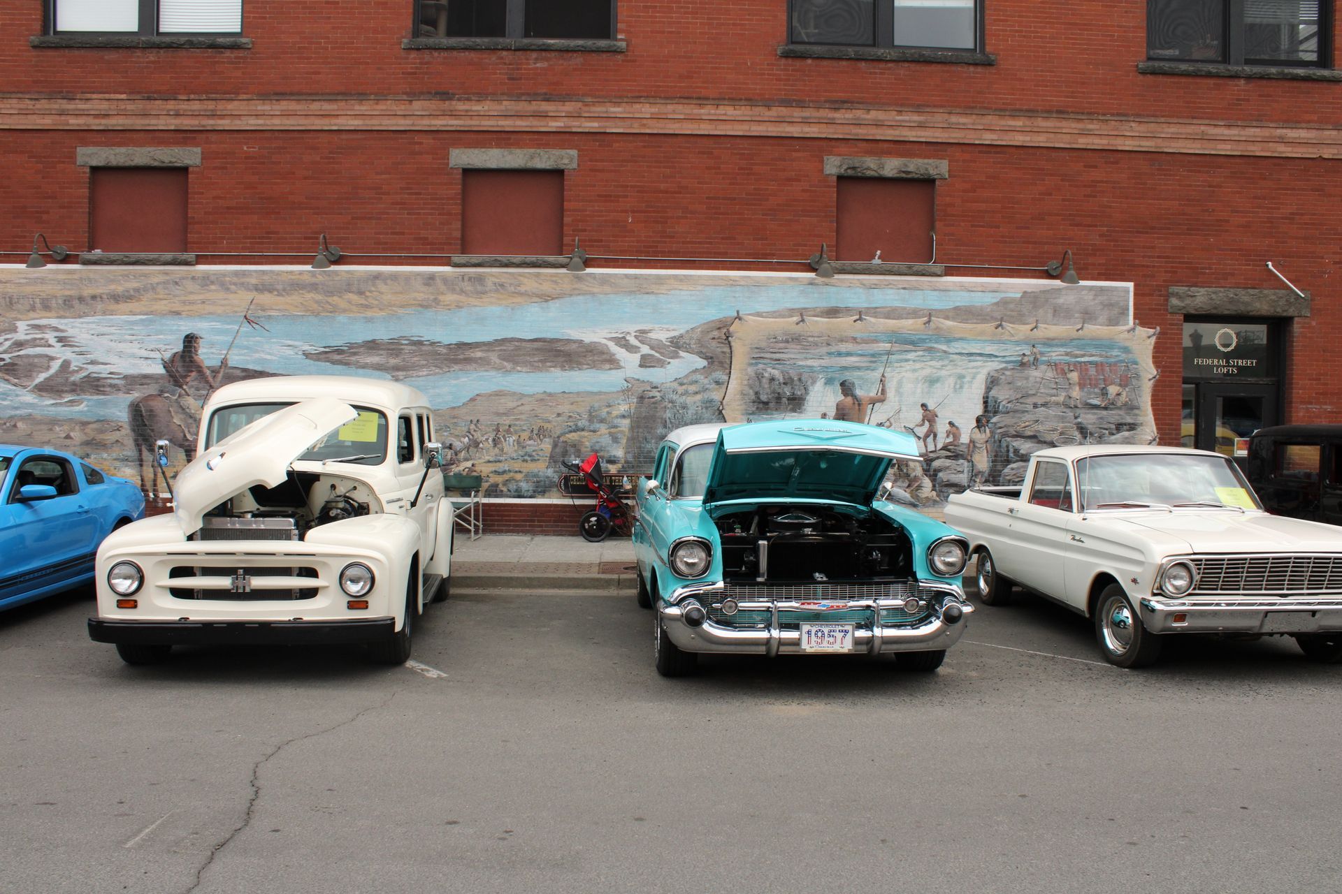 Three old cars are parked in front of a brick building