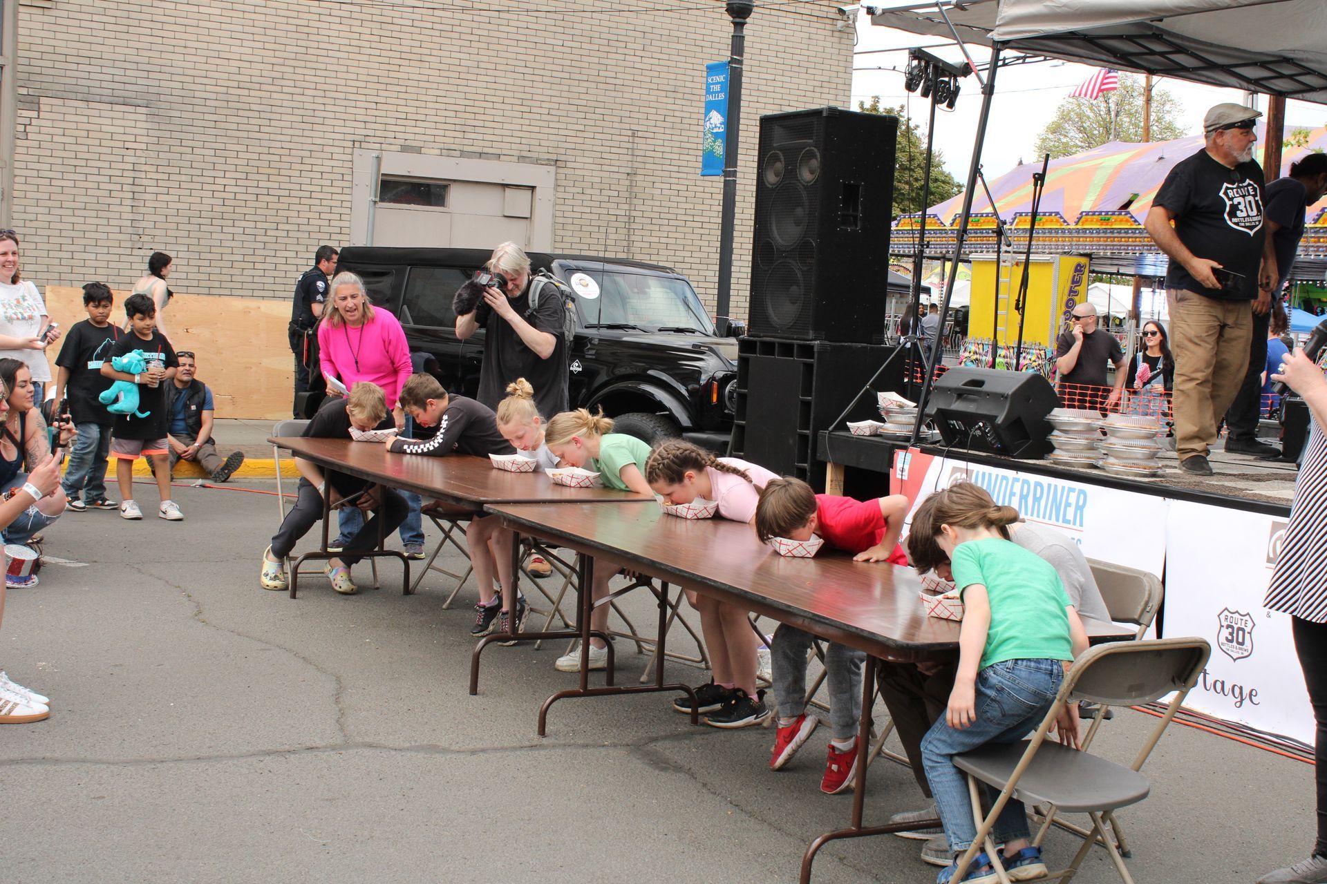 A group of children are sitting at a long table with their heads down.