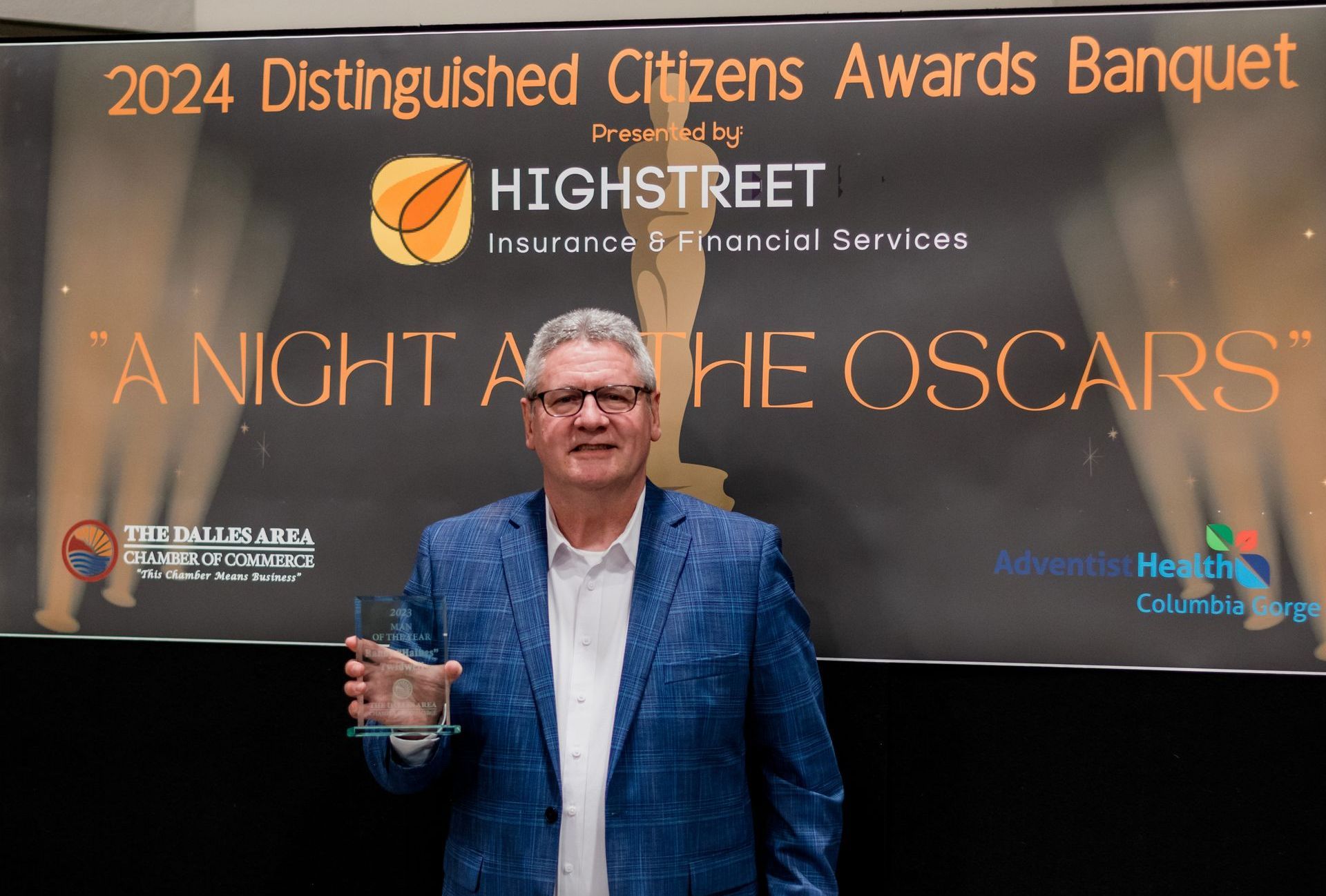 A man is standing in front of a sign that says 2024 distinguished citizens awards banquet