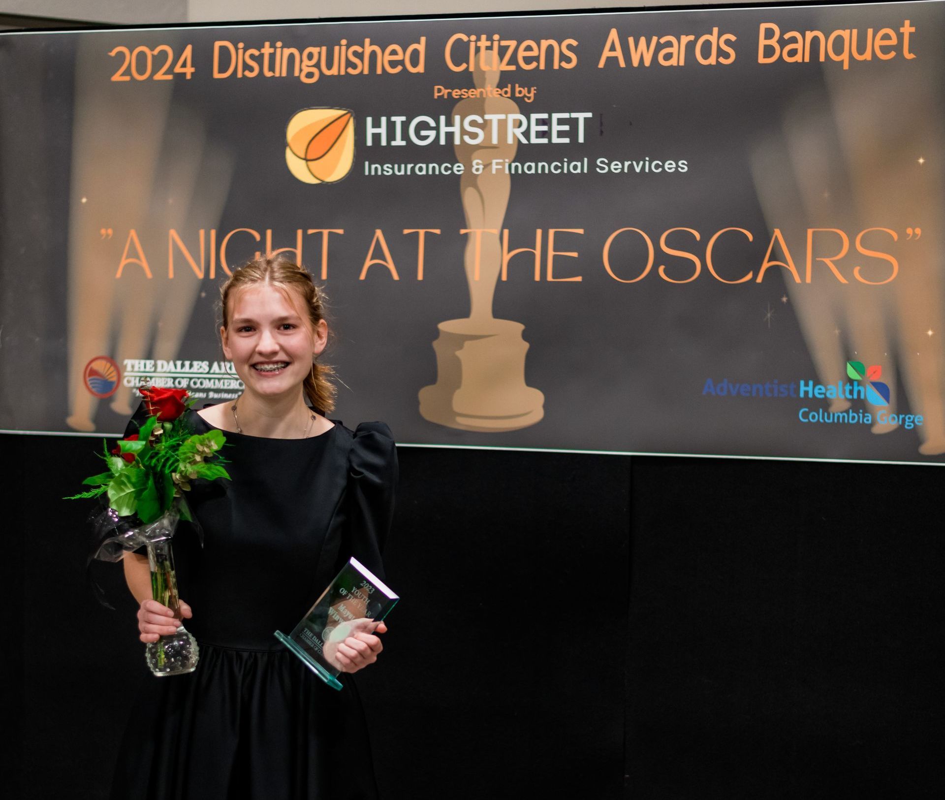 A woman in front of a sign that says 2024 distinguished citizens awards banquet