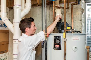 Technician inspecting a home furnace and ductwork in a utility room