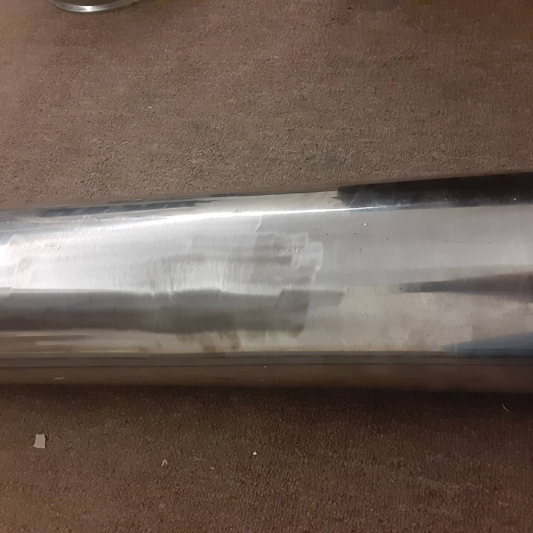 A close up of a metal pipe sitting on top of a brown carpet.