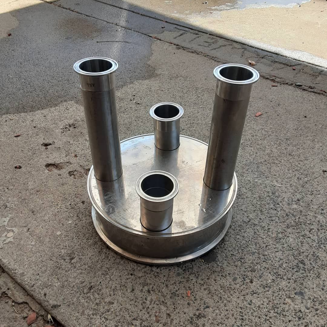 A metal object with four holes in it is sitting on the ground.