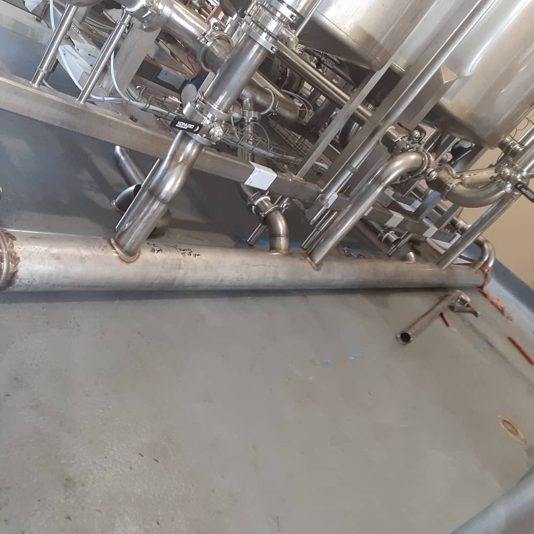 A stainless steel pipe is connected to a machine in a factory.