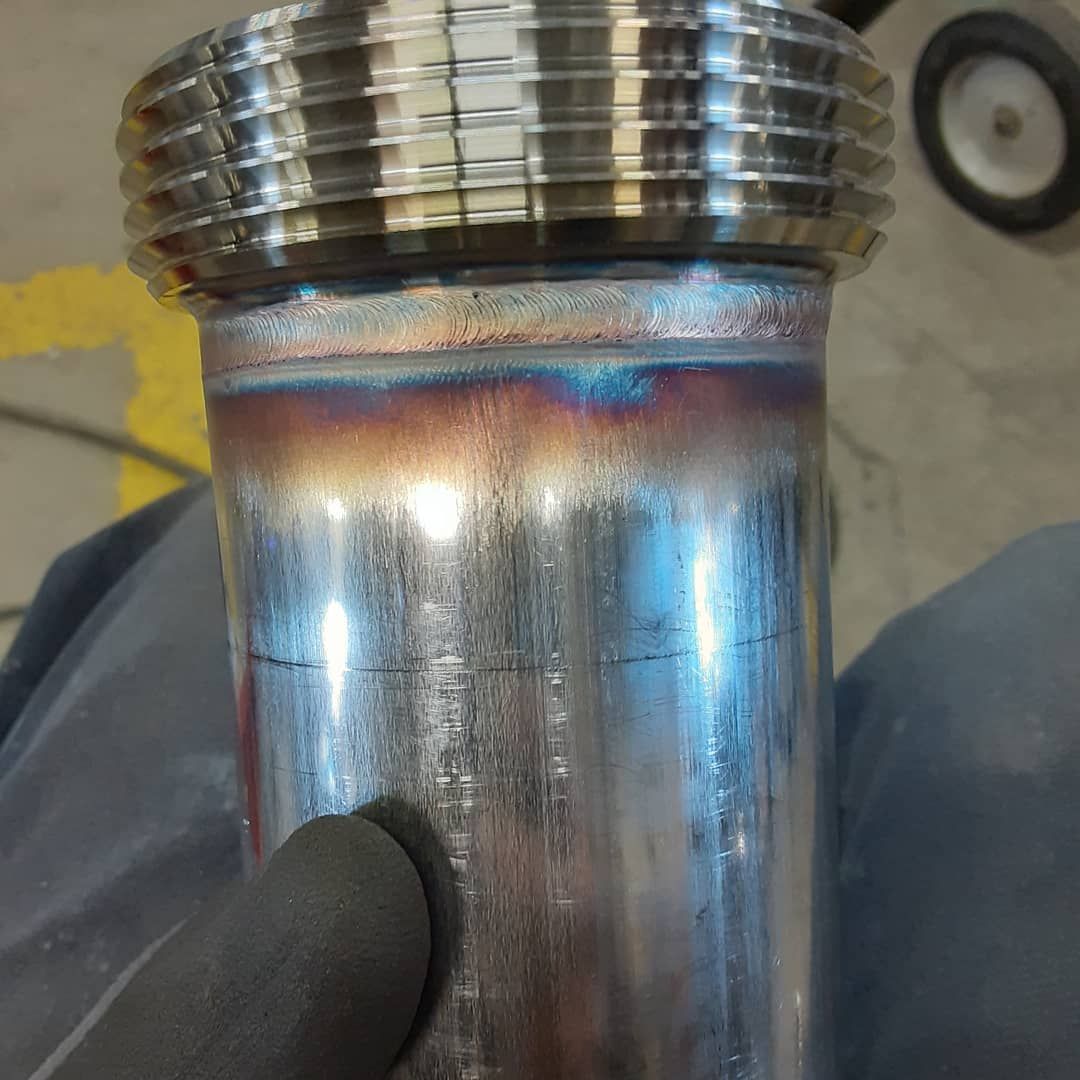 A person is welding a metal pipe in a garage.