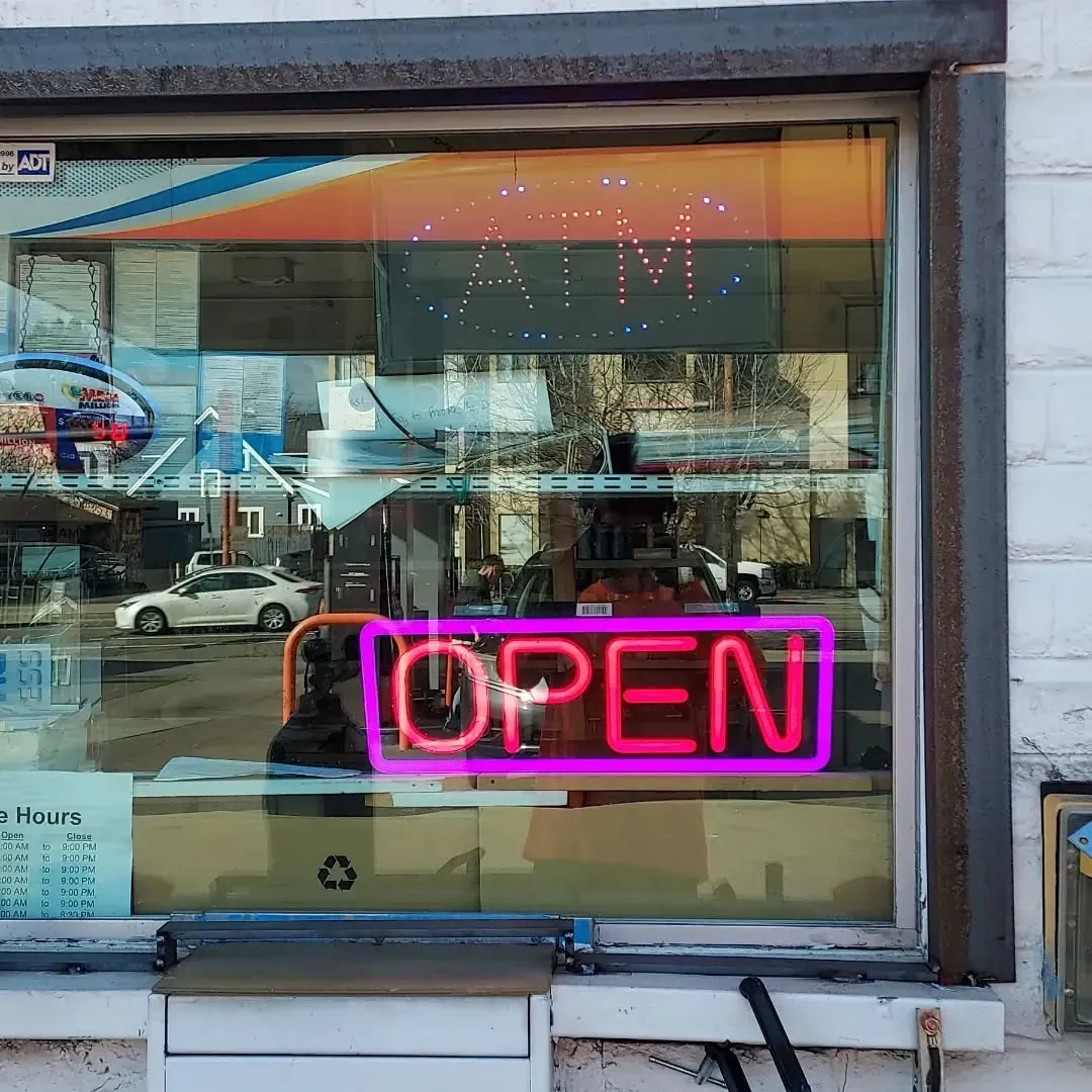 A neon sign in a window that says open