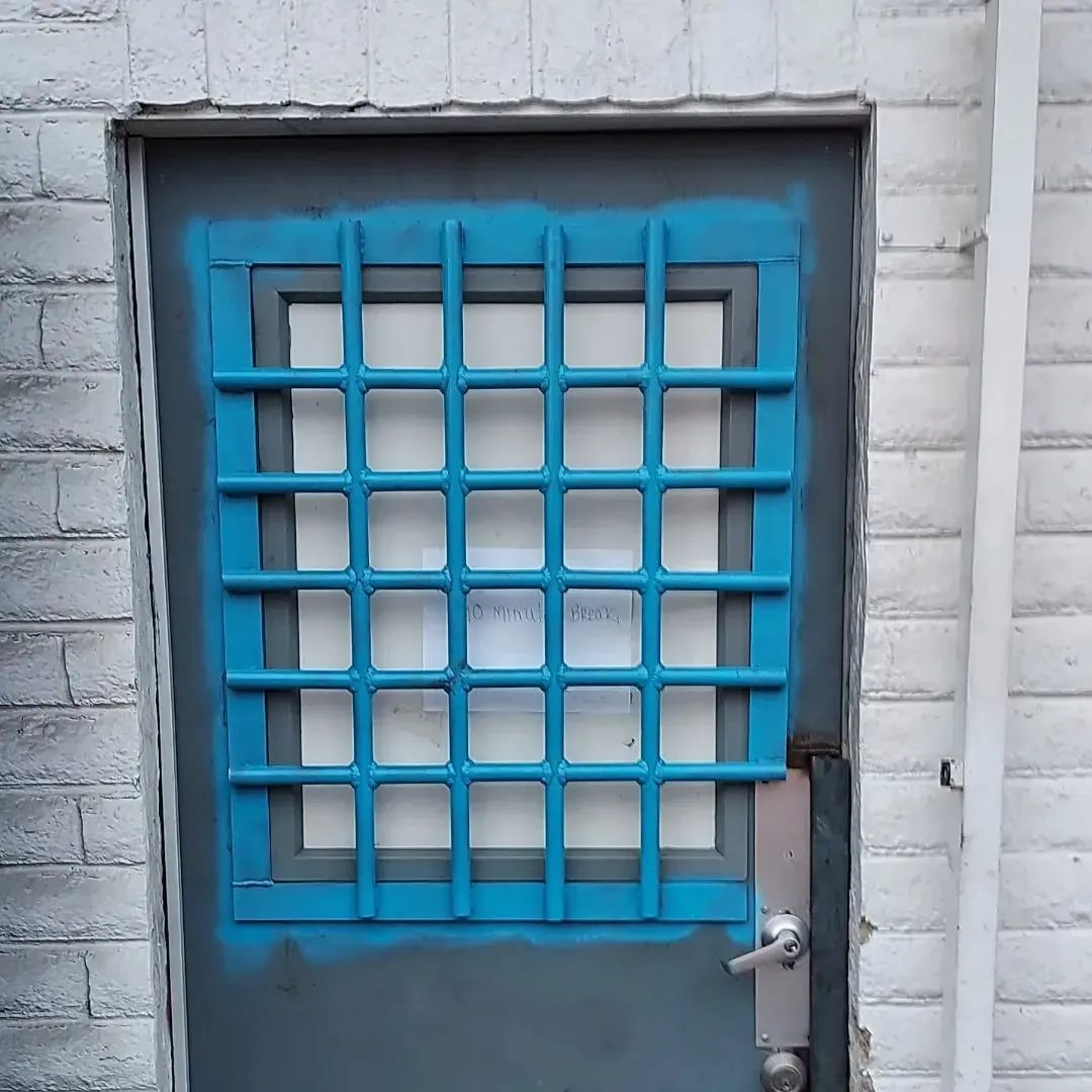 A blue door with squares on it is on a white brick wall
