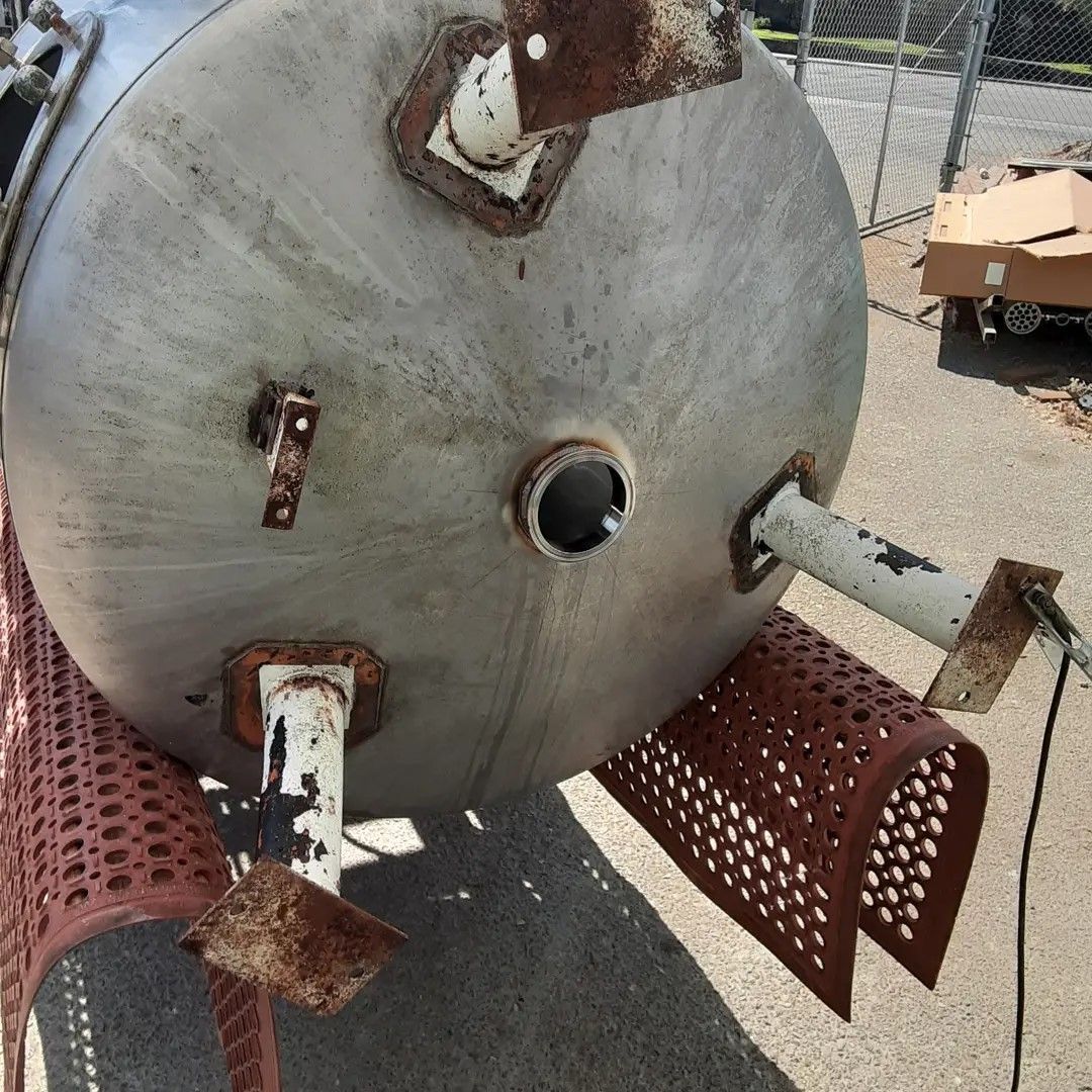 A large stainless steel tank is sitting on top of a red table.