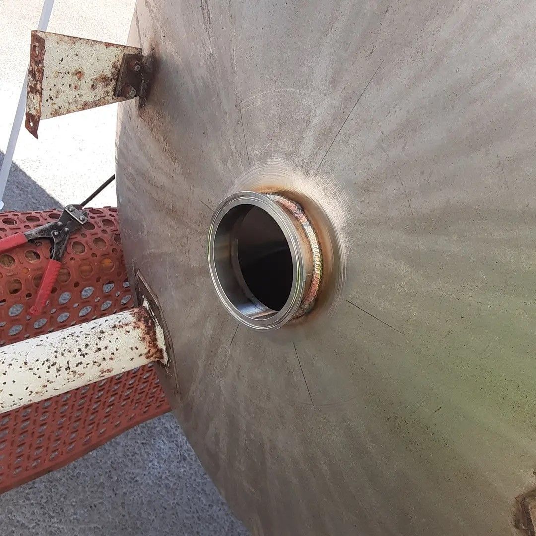 A close up of a stainless steel tank with a hole in it.