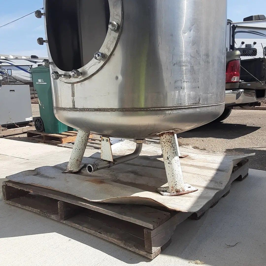 A large stainless steel tank is sitting on top of a wooden pallet.