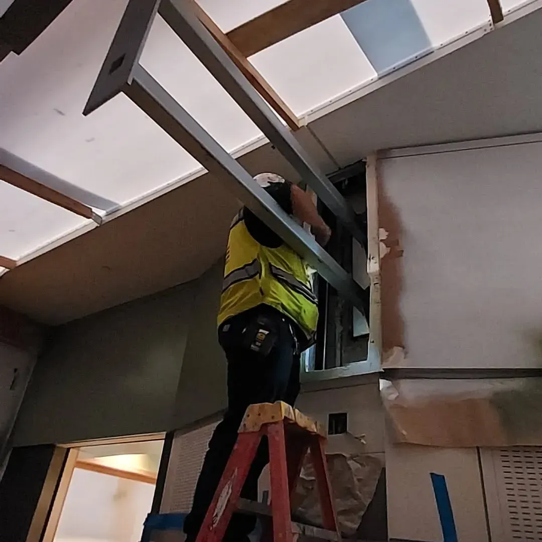 A man is standing on a ladder working on a ceiling