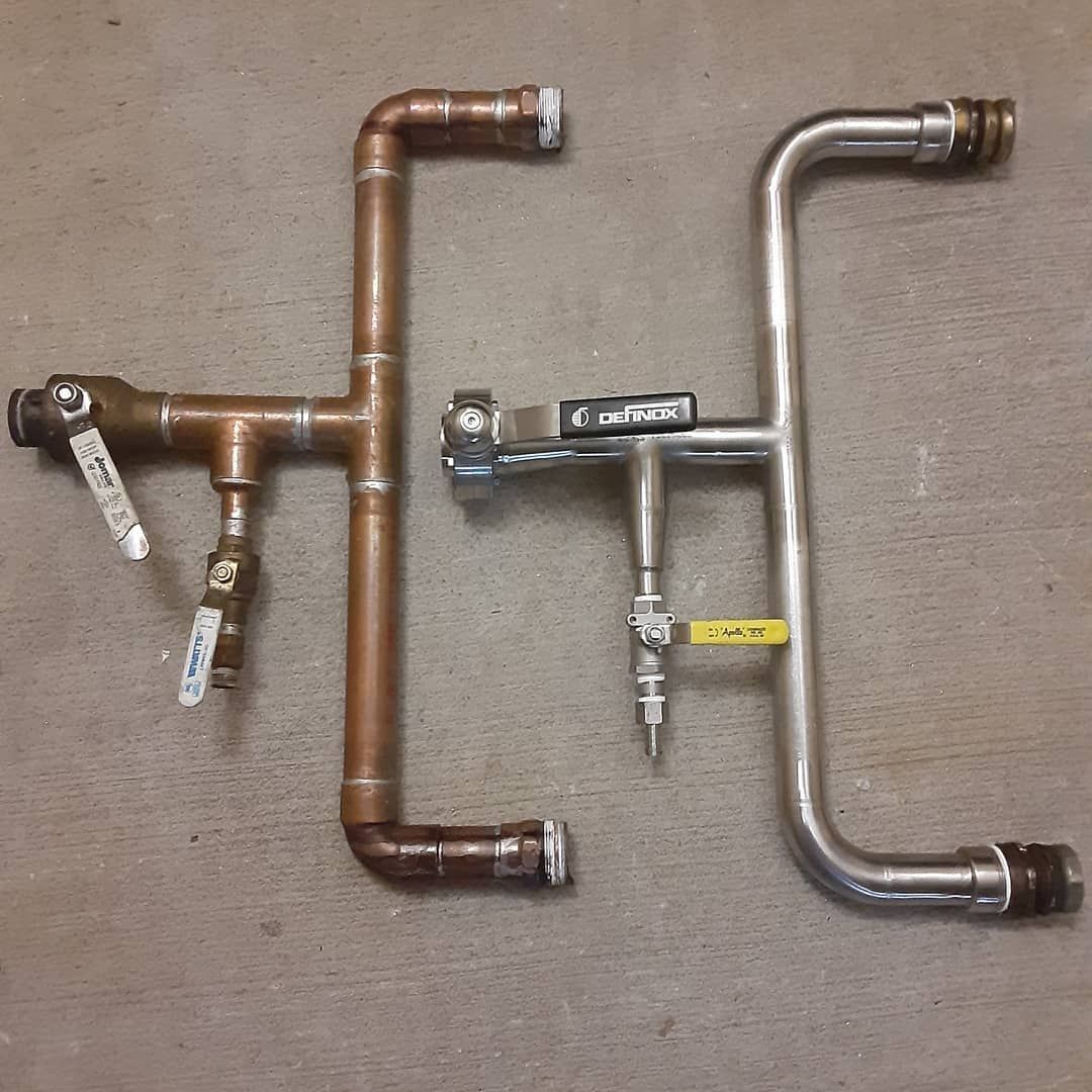 Two copper pipes with valves on them are sitting on a carpet.