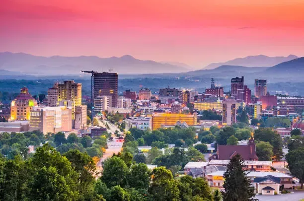 An aerial view of a city with mountains in the background at sunset.