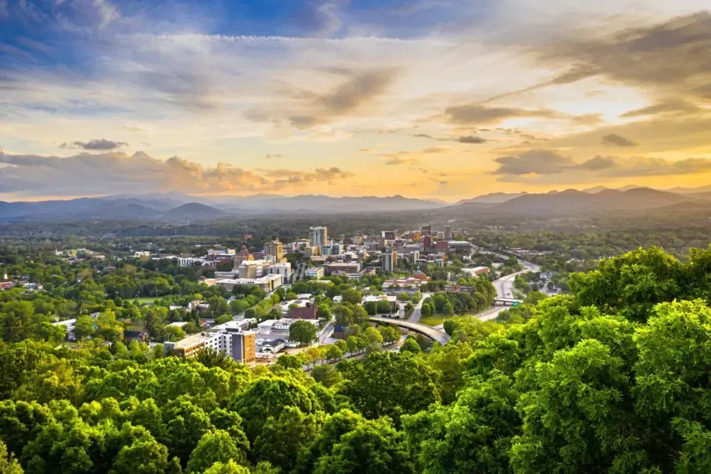 An aerial view of a city surrounded by trees at sunset.