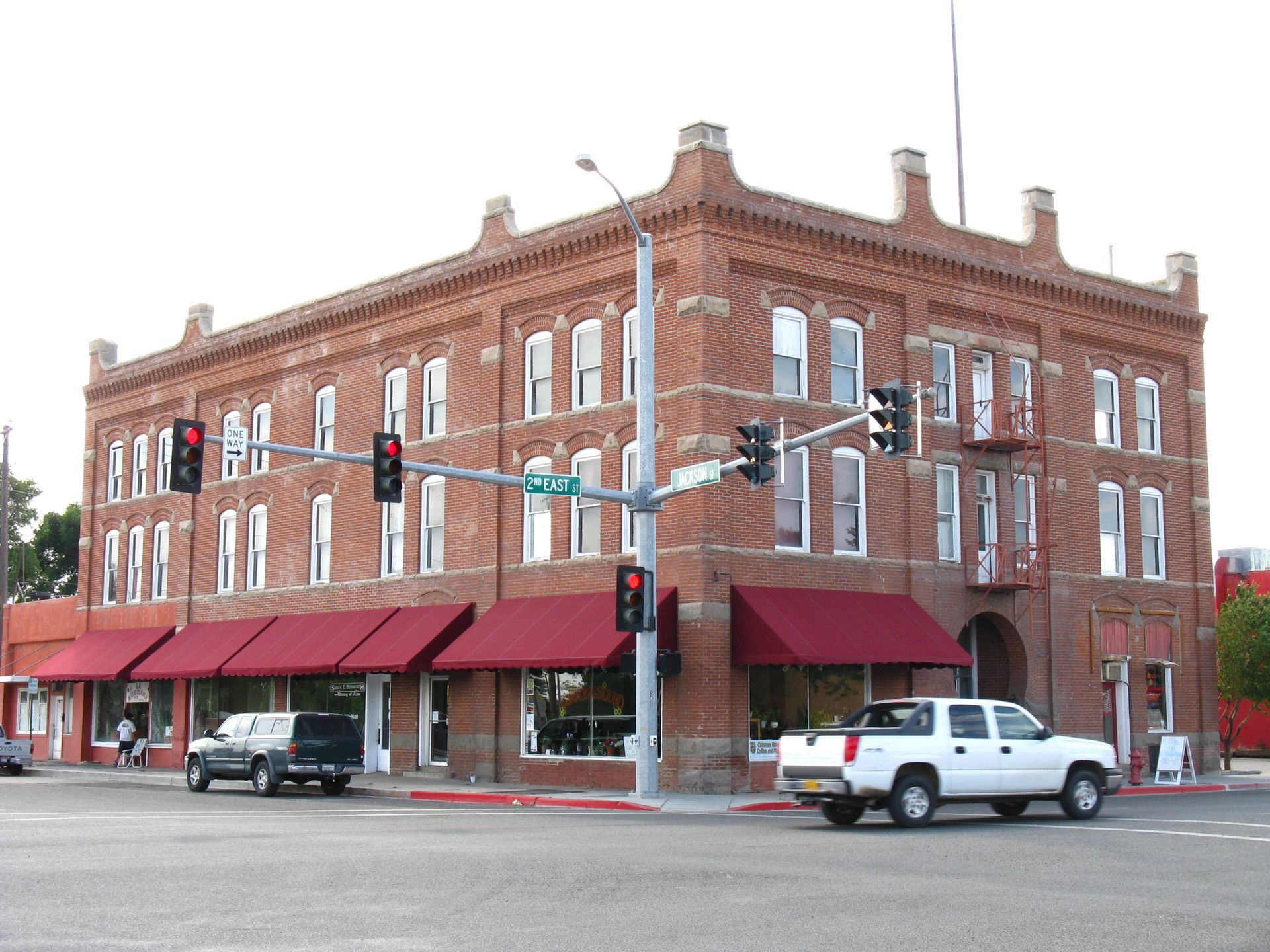 A white truck is parked in front of a large brick building