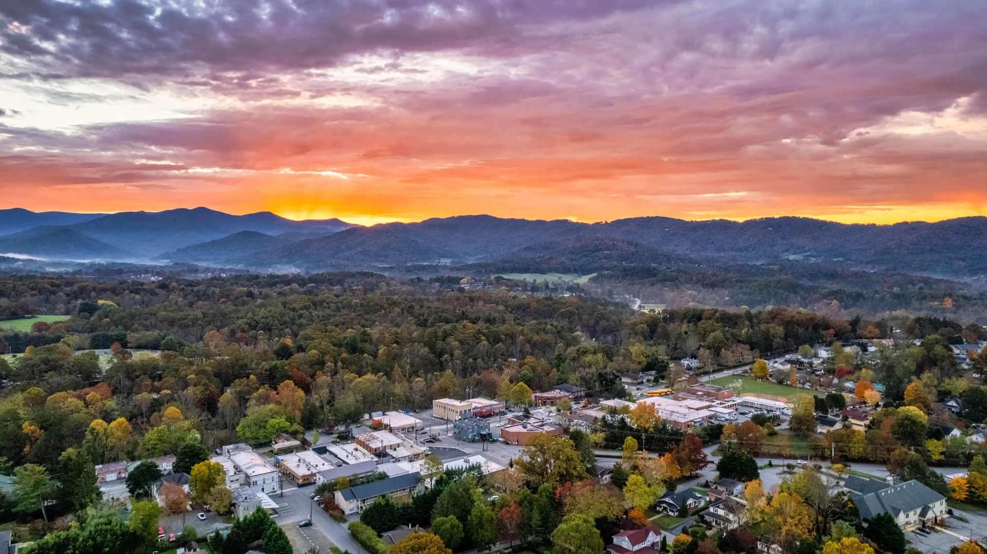 An aerial view of a city at sunset with mountains in the background.